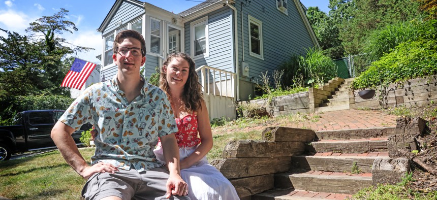 Young couple, Nick and Elizabeth Ruland sit in front of their first new home in Rocky Point, New York.