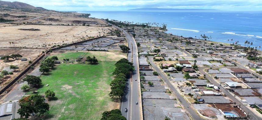 In an aerial view, lots that have been cleared of wildfire debris and covered in gray gravel, are seen as vehicles pass along a newly reopened stretch of Honoapi'ilani Highway on August 03, 2024 in Lahaina, Hawaii. 