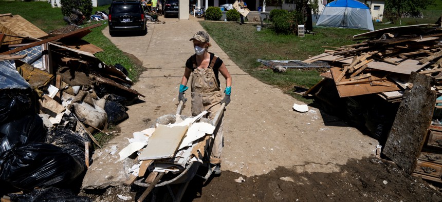 A volunteer walks a wheelbarrow to a pile of debris during clean up in Perry County, Kentucky near Hazard on August 6, 2022, after devastating rain storms flooded the area.