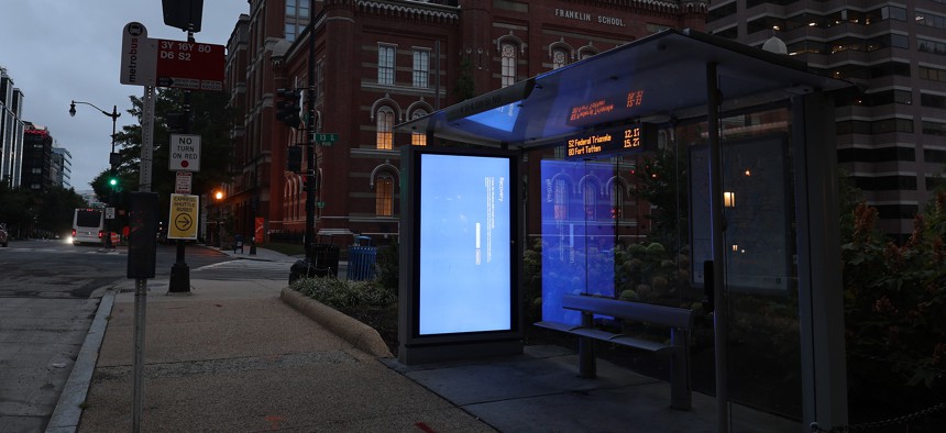 A blue Windows error message caused by the CrowdStrike software update is displayed on a screen in a bus shelter in Washington, D.C.