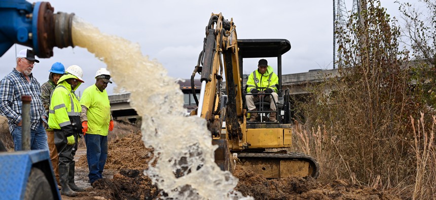 Water is redirected from a damaged water main break along McLaurin Road as workers try to figure out how to fix the broken pipe on December 29, 2022 in Jackson, Miss.