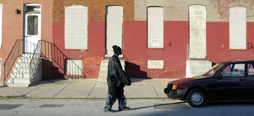 A pedestrian passes boarded up row houses in the Middle East neighborhood, three blocks north of Johns Hopkins University Medical School, on Dec. 2, 2003, in East Baltimore, Maryland. 