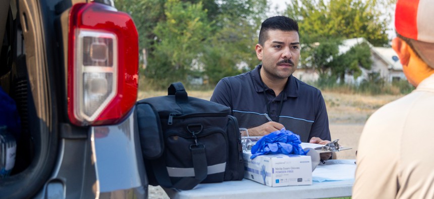 Alex Dominguez with Idaho Central District Health performs health tests for agricultural workers in Hammett, Idaho. The tests are intended to help the farmworkers better understand how hot weather can affect them.