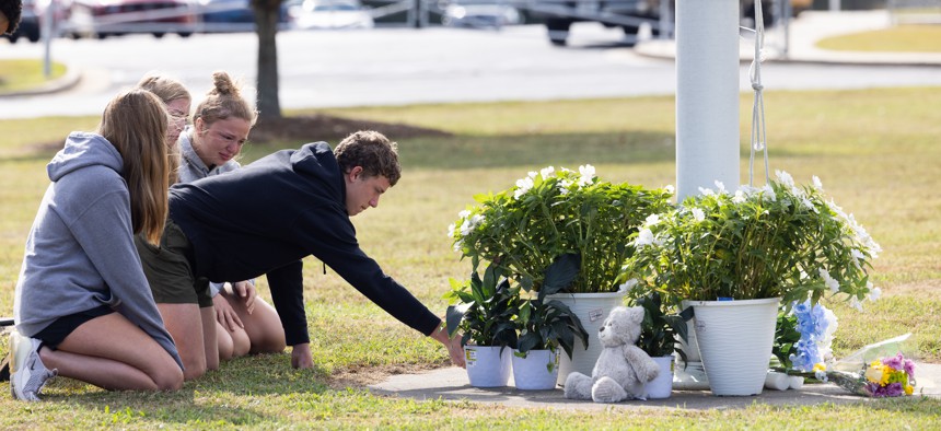 Students kneel in front of a makeshift memorial in front of Apalachee High School in Winder, Georgia. Two students and two teachers were shot and killed at the school on September 4.