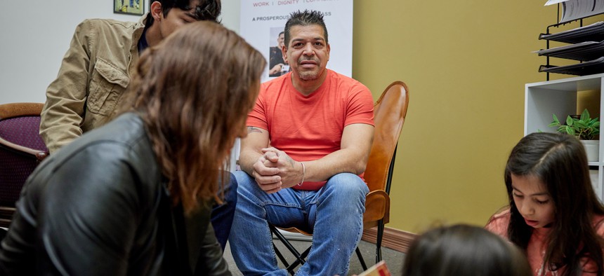 A Venezuelan immigrant who is seeking asylum sits with his family at the Centro de Trabajadores n Denver. 