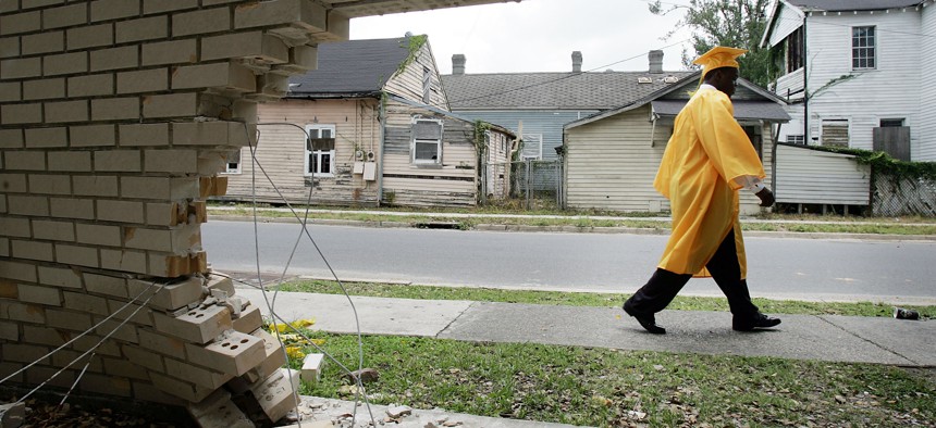 James Holloway, 20, from John McDonogh Senior High School's first graduating class since Hurricane Katrina walks past a damaged wall on his way his commencement June 8, 2007 in New Orleans.