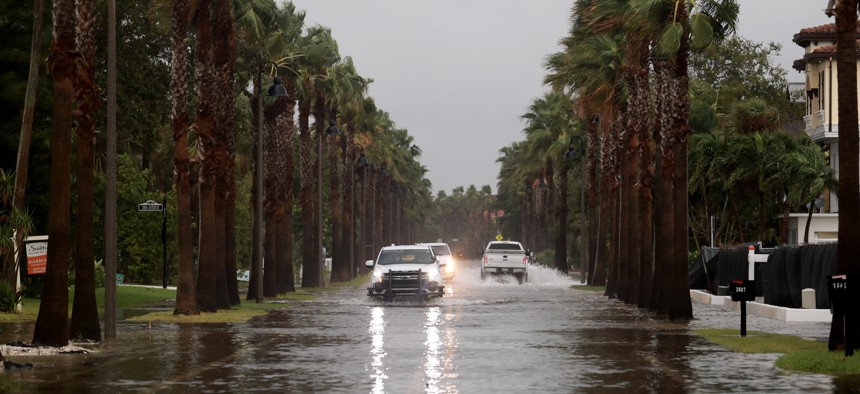 Vehicles drive along a flooded street as Hurricane Helene churns offshore on September 26, 2024 in St. Pete Beach, Fla.