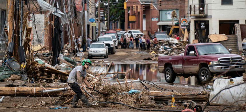 Workers, community members, and business owners clean up debris in the aftermath of Hurricane Helene in Marshall, N.C., on Monday, Sept. 30, 2024.