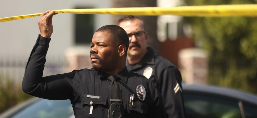 A police officer holds up yellow tape from a double homicide shooting in South Los Angeles on June 1, 2024.