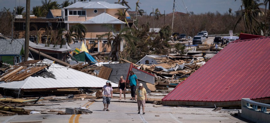 People walk pass destroyed houses and businesses in the aftermath of Hurricane Ian in Matlacha, Fla., on Oct. 1, 2022.