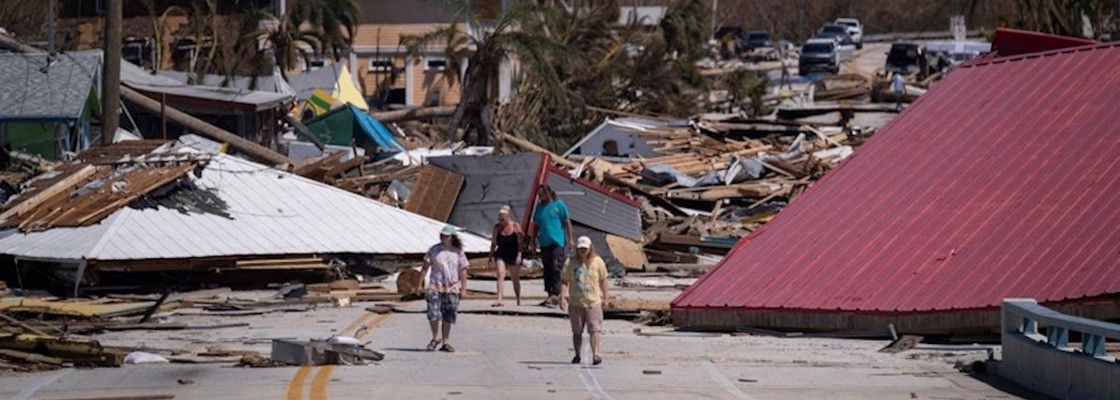 People walk pass destroyed houses and businesses in the aftermath of Hurricane Ian in Matlacha, Fla., on Oct. 1, 2022. 