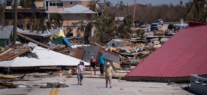 People walk pass destroyed houses and businesses in the aftermath of Hurricane Ian in Matlacha, Fla., on Oct. 1, 2022. 