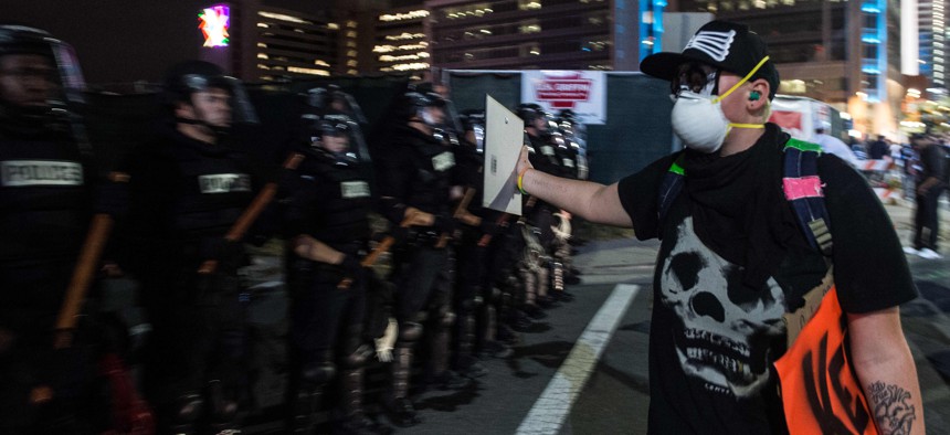 A protester holds a mirror up to police officers forming a containment line in Charlotte, North Carolina.