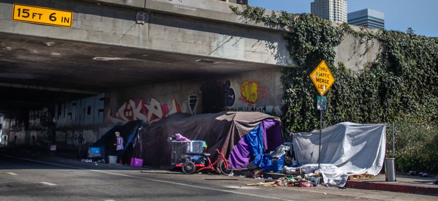 A person stands next to an encampment in Skid Row in downtown Los Angeles on July 26, 2024.