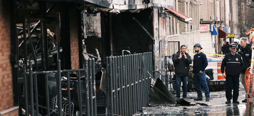 Fire officials and others gather outside of a Bronx supermarket the day after a fire tore through a market that fire officials are blaming on a faulty lithium-ion battery on March 6, 2023, in New York City. 