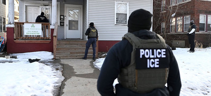 ICE agents approach a house before detaining two people on Jan. 13, 2026 in Minneapolis.