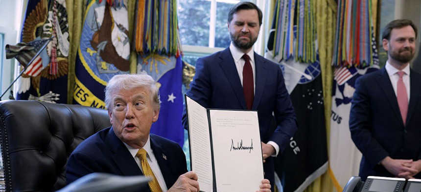 U.S. President Donald Trump holds up a document that he signed as Vice President JD Vance (C) and Federal Trade Commission Chairman Andrew Ferguson look on during a White House signing ceremony in the Oval Office of the White House on March 16, 2026 in Washington, DC. Trump signed an executive order to create a task force on fraud which will be lead by Vice President J.D. Vance.