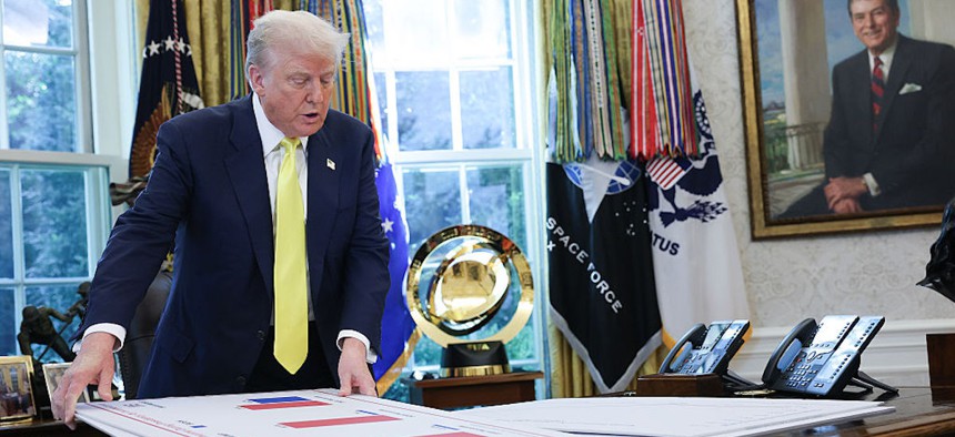 U.S. President Donald Trump shuffles through charts on his desk with economic data in the Oval Office on Aug. 7, 2025, in Washington, DC. 