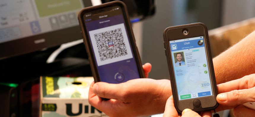 A Harmons Grocery Store employee does a demonstration as she scans a QR Code (R) from a customers phone (L) to verify his age on a beer purchase at a Harmons Grocery store on Aug. 4, 2021, in Salt Lake City. Utah is the first state in the nation to start to convert and offer digital driver licenses on mobile devices