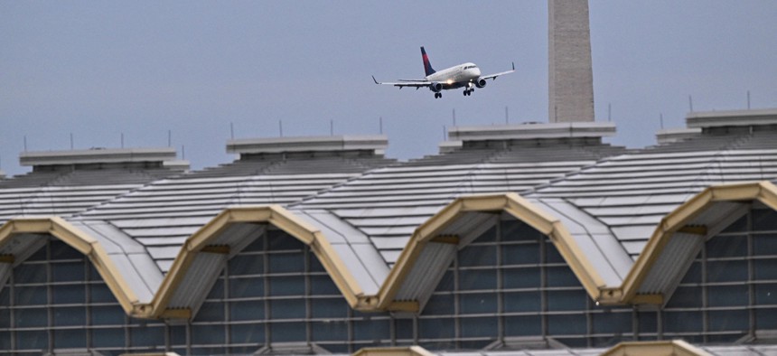 A commercial jet approaches the runway at Ronald Reagan International Airport near the Washington Monument (background) and the airport terminal in Arlington, Virginia, on February 2, 2025.