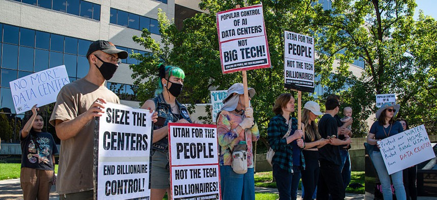 Demonstrators hold signs reading ''Utah For The People Not The Tech Billionaires!'' and ''Sieze The Centers'' during a community protest opposing a proposed data center zoning ordinance outside the Utah County Administration Building in Provo, Utah, on Oct. 7, 2026.