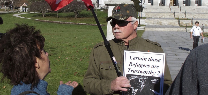 Bronwyn Fryer, left, and Rick Lawrence debate Friday Nov. 20, 2015 in front of the Statehouse in Montpelier, Vt., whether Syrian refugees should be brought to the state.