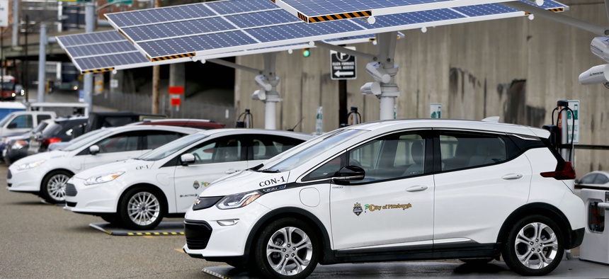 Some of the city of Pittsburgh's fleet of electrical vehicles are parked under solar charging panels before a news conference announcing the facility debut, Wednesday, April 18, 2018, in Pittsburgh.