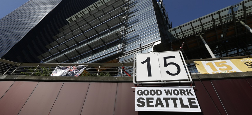 A sign that reads "15 Good Work Seattle" is displayed below Seattle City Hall, right, and the Columbia Center building, left, Monday, June 2, 2014, after the Seattle City Council passed a $15 minimum wage measure.