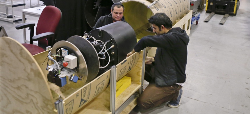 In this April 4, 2018 photo, David Kohandash, left, and Mohammad Mousaei work on the RadPiper robot in the robotics institute at Carnegie-Mellon University in Pittsburgh.