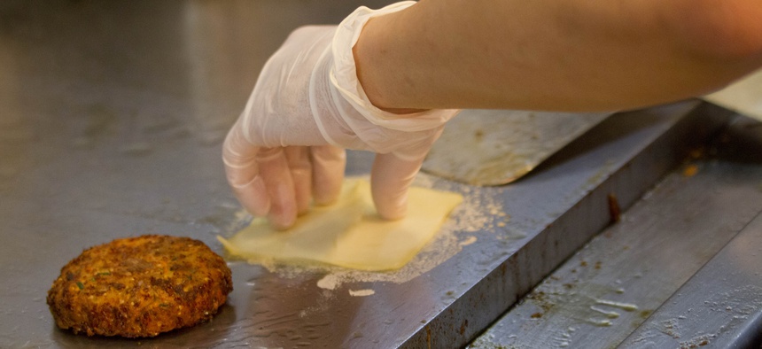In this Tuesday, Jan. 27, 2015, photo, a BurgerFi restaurant employee prepares to add cheese to a veggie burger as she grills an order at the Aventura, Fla., restaurant.