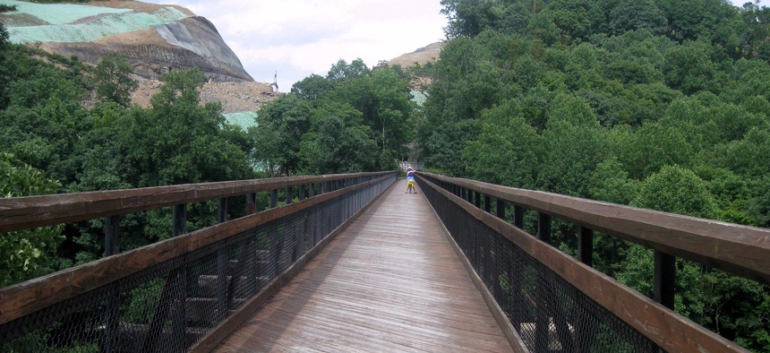 In this July 13, 2012, file photo, a bicyclist participating in a three-day ride of the Great Allegheny Passage between Pittsburgh and Cumberland, Md., crosses a bridge near Confluence, Pa.