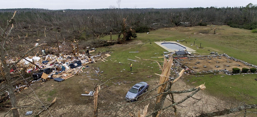 Debris from a home litters a yard the day after a tornado blew it off its foundation, at right, in Beauregard, Ala., Monday, March 4, 2019.