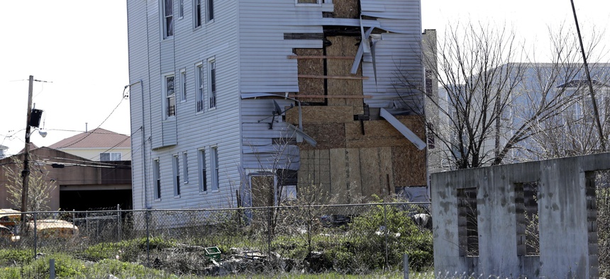 In this April 26, 2018, photo boards cover up the back of a building near the foundation of a construction site in a so-called “opportunity zone” in Newark, N.J.