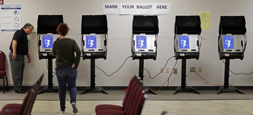 In this Oct. 19, 2017, file photo, Kelly Monroe, investigator with the Georgia secretary of state office, left, takes a look at a new voting machine being tested at a polling site in Conyers, Ga.