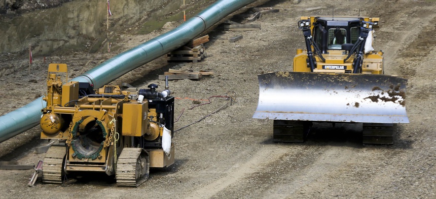 An operator moves a bulldozer along a section of assembled pipe lined up along a cleared section of woods where a pipeline for shale gas is under construction on Saturday, July 8, 2017, in Jackson Township, Pa.