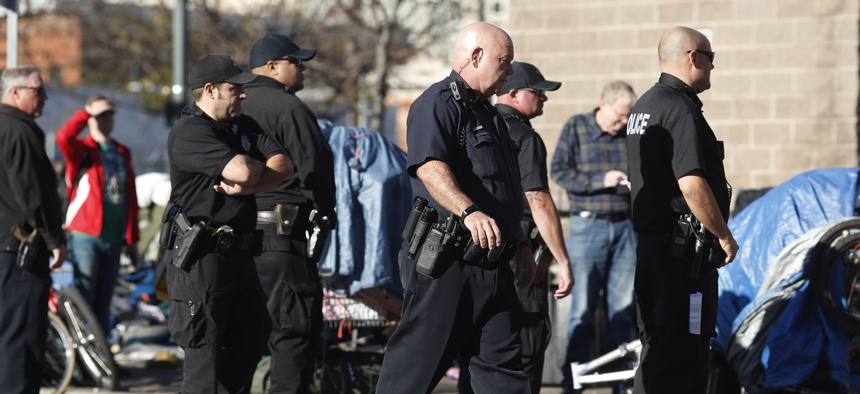 Denver Police Department officers keep watch during a sweep of homeless people who were living on the walks surrounding a shelter near the baseball stadium Tuesday, Nov. 15, 2016, in downtown Denver.