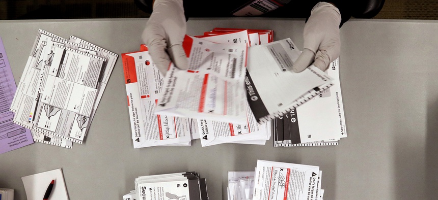 An election worker separates ballots from security envelopes at the King County Elections office Wednesday, Nov. 7, 2018, in Renton, Wash.