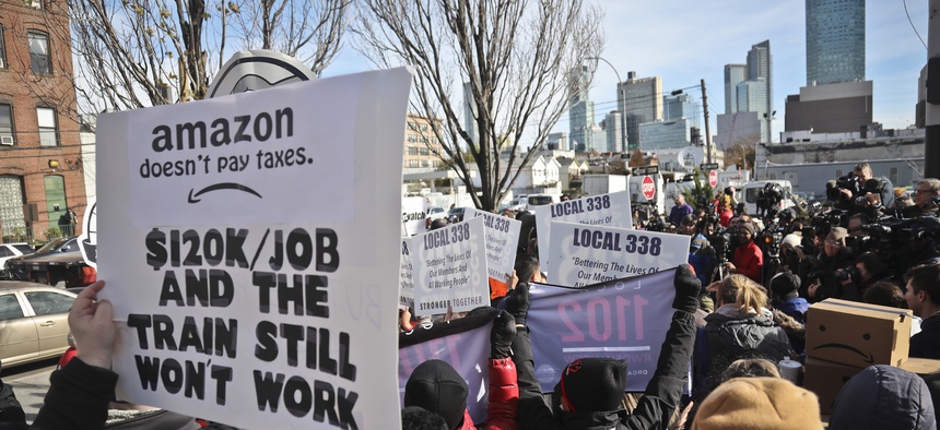 In this Nov. 14, 2018, file photo protesters carry anti-Amazon posters during a coalition rally and press conference opposing Amazon headquarters getting subsidies to locate in the New York neighborhood of Long Island City.