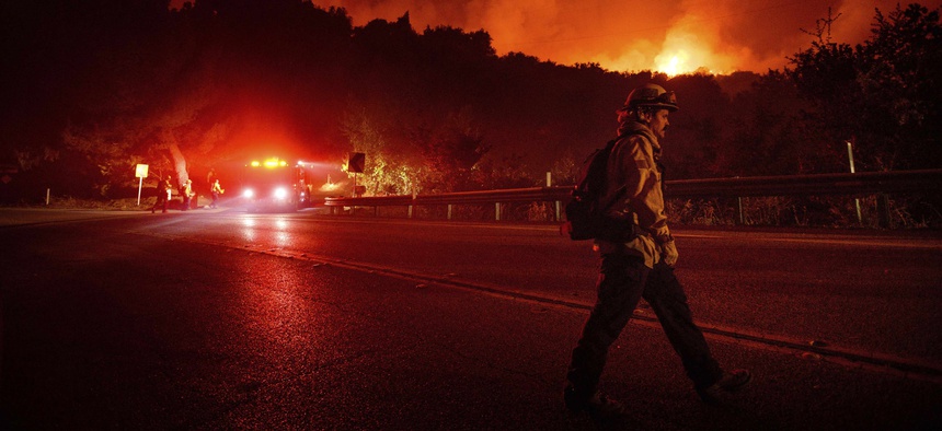 A firefighter crosses Highway 154 while battling the Cave Fire in Los Padres National Forest, Calif., above Santa Barbara on Tuesday, Nov. 26, 2019.