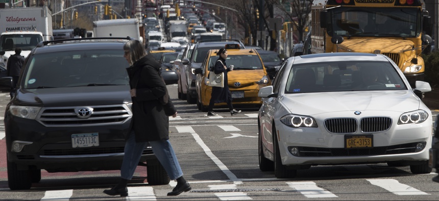 In this March 2019 photo, pedestrians cross Delancey Street as traffic is seen making its way into Manhattan from Brooklyn over the Williamsburg Bridge, in New York.