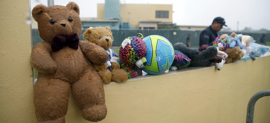 In this Saturday, June 23, 2018 photo, a guard walks by toys protesters left for migrant children in Homestead, Fla. Foster care advocates say some children will end up in the American foster care system.