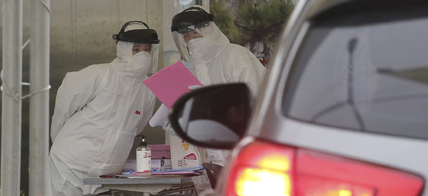 Medical staffers wearing protective suits work to take samples from drivers with suspected symptoms of the coronavirus at a "drive-through" virus test facility in Goyang, South Korea on March 1, 2020.