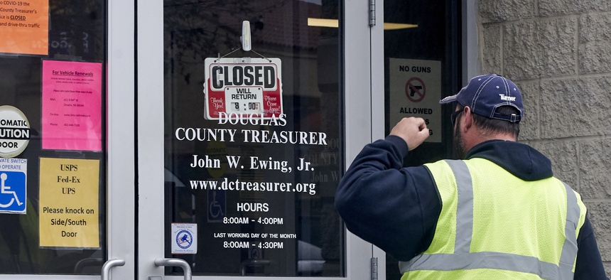 A man is confronted with a closed sign at the Douglas County Treasurer's office in Omaha, Neb. on March 18, 2020. In-person services were suspended due to the coronavirus outbreak.
