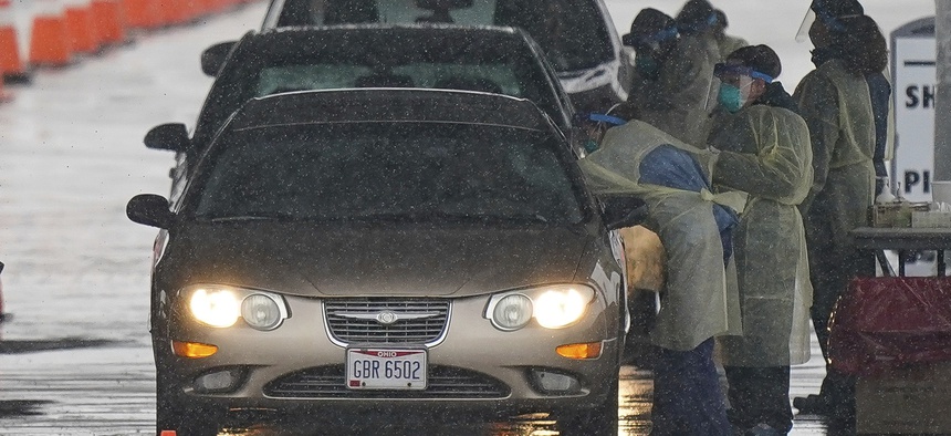 Healthcare workers with Premier Health Ohio collect samples to be tested for COVID-19, the disease that is caused by the new coronavirus, at a at a drive-by collection site at The University of Dayton Arena parking lot, in Dayton, Ohio, March 18, 2020.