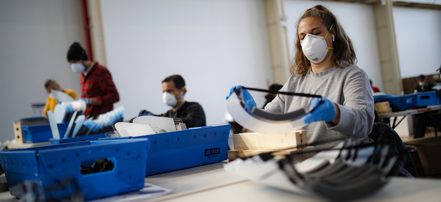 A worker wearing personal protective equipment builds a splash guard during a mass manufacturing operation to supply New York City government with protection to distribute against COVID-19 transmission, March 27, 2020, at the Brooklyn Navy Yard.