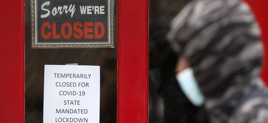 In this May 7 photo, a pedestrian walks by The Framing Gallery, closed due to the COVID-19 pandemic, in Grosse Pointe, Mich.