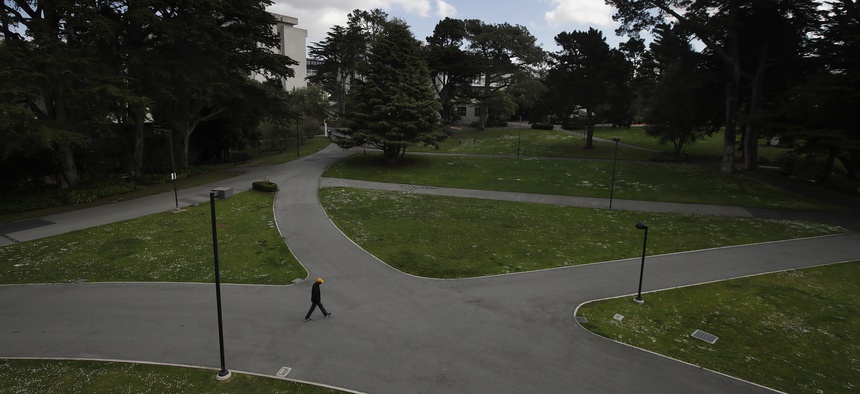 A man walks alone on a path on the campus of San Francisco State University, part of the California State University system, on March 19, 2020.