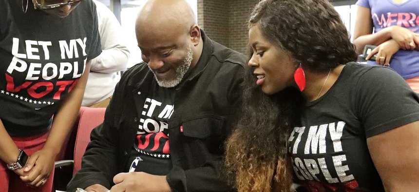 Desmond Meade, who previously had a felony conviction and is president of the Florida Rights Restoration Coalition, fills out a voter registration form as his wife Sheena looks on at the Supervisor of Elections office on Jan. 8, 2019, in Orlando, Fla.