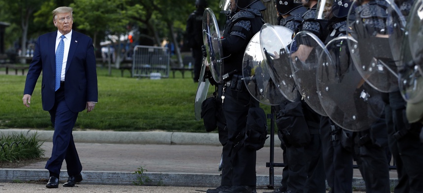President Donald Trump walks past police in Lafayette Park after he visited outside St. John's Church across from the White House Monday, June 1, 2020, in Washington.