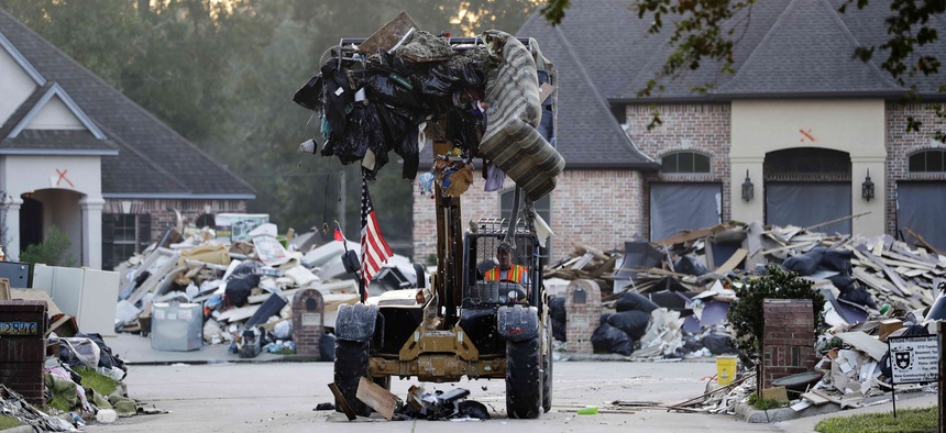 A worker cleans up debris in a neighborhood flooded by Hurricane Harvey in Beaumont, Texas, Tuesday, Sept. 26, 2017.